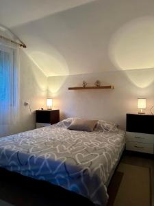 a bed in a bedroom with two lights on the wall at Vikendica Cokori in Banja Luka