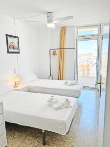 2 łóżka w białym pokoju z oknem w obiekcie Tahiti - Frente al Mar - Gran Terraza - Parking Gratis w mieście El Campello