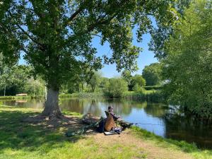 a man sitting under a tree with a fishing rod at Oak Apple in Plaitford