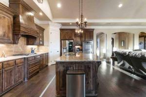 une grande cuisine avec des placards en bois et un grand îlot dans l'établissement Luxe Retreat: Pool, Spa,Jacuzzi, EV Charger & more, à DeCordova