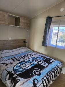 a bedroom with a bed with a painting on it at Cottage dans un camping 4 étoiles in La Teste-de-Buch