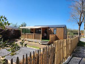 a wooden cabin with a fence in front of it at Cottage dans un camping 4 étoiles in La Teste-de-Buch
