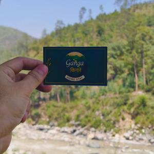 a person holding up a card in front of a river at Ganga Kinaare in Uttarkāshi