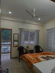 a bedroom with a bed and two chairs and windows at Ganga Kinaare in Uttarkāshi