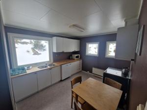 a kitchen with white cabinets and a table and a window at Gamle Fiskarheimen i Sund in Sund