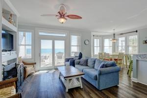 a living room with a blue couch and a table at 1322 New River Inlet Road- Oceanfront, 240 EV outlet, Elevator, Sleeps 18, Hot tub in North Topsail Beach