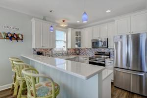 a kitchen with white cabinets and a stainless steel refrigerator at 1322 New River Inlet Road- Oceanfront, 240 EV outlet, Elevator, Sleeps 18, Hot tub in North Topsail Beach