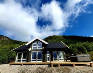 a small house with a black roof on a hill at Explorers Cabin Lofoten in Offersøya