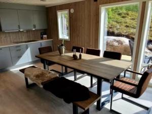 a kitchen and dining room with a wooden table and chairs at Explorers Cabin Lofoten in Offersøya +15 photos