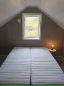 a bed in a room with a small window at Explorers Cabin Lofoten in Offersøya