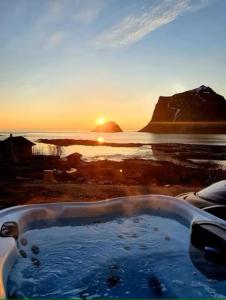 a bath tub with the sunset in the background at Explorers Cabin Lofoten in Offersøya