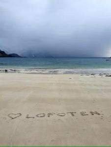 a sign written in the sand on a beach at Explorers Cabin Lofoten in Offersøya