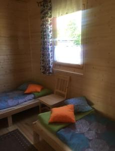 eine Blockhütte mit 2 Betten und einem Fenster in der Unterkunft Domek u Niny nad jeziorem Niesłysz in Przełazy