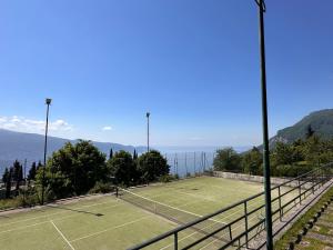 a tennis court with trees and mountains in the background at Heike in Tignale