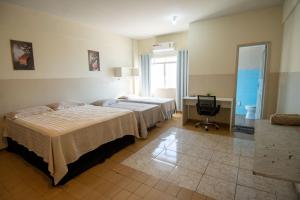 a hotel room with two beds and a television at Hotel Centro in Corumbá