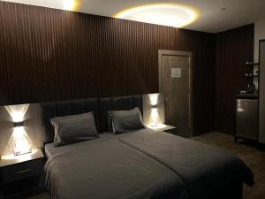 a bedroom with a large bed with two lamps at Caprios motel in Al Qasţal