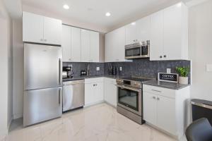 a kitchen with white cabinets and stainless steel appliances at Ammos Luxury Living- Zakinthos Suite in Ventnor City
