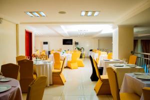a restaurant with white tables and yellow chairs at King Maya Hotel in Brazzaville