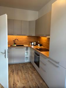 a kitchen with white cabinets and a wooden floor at Macabu Apartment Sophie in Zwickau