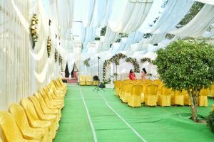 a banquet hall with yellow chairs and white curtains at Sunny Villa in Sivasagar