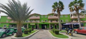 Un edificio verde con coches aparcados en un estacionamiento. en Sal service green moradias residence with pool, en Santa Maria