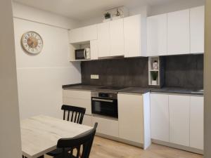 a kitchen with white cabinets and a table and a clock at Patxikuenea in Zarautz