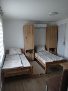 two beds in a room with wooden cabinets at Soba Ðorović 3 in Postenje