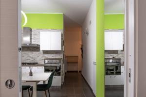 a kitchen with green and white walls and a table at Via Vai Guest House in Battipaglia