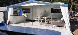 a tent with a couch and a kitchen on a deck at Przyczepa kempingowa Happy Place Hel - Camping Kormoran in Hel