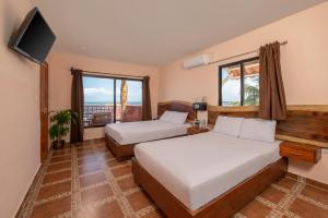 a hotel room with two beds and a television at Hotel El Perico Marinero in Río Lagartos