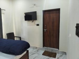 a room with a door and a bed and a television at Hotel Grand View in Barkot
