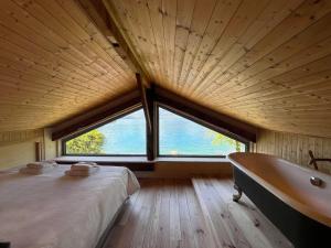 a bedroom with a tub and a bed and a large window at Chalet les pieds dans l'eau avec accès direct au Lac d'Annecy in Angon