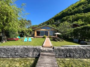 a house on the side of a hill with a wooden bridge at Chalet les pieds dans l'eau avec accès direct au Lac d'Annecy in Angon