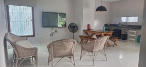 a living room with chairs and a table and a tv at Casa praia Paracuru in Paracuru
