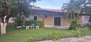 a house with a yard with two benches and palm trees at Casa praia Paracuru in Paracuru