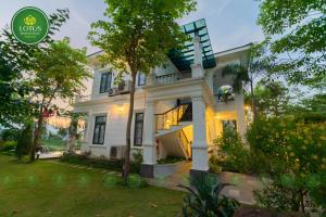 a white house with a tree in the yard at Lotus Hotel Vuon Vua Phu Tho in Phú Thọ
