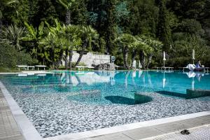 Una gran piscina con agua azul y palmeras. en Hotel Terme Millepini, en Montegrotto Terme