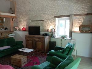 a living room with two green chairs and a television at La grange d'Isabelle in Rouillac