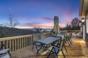 a deck with a table and chairs and an umbrella at Van Kirk Cove - 6 BDR Stunner in Branson West