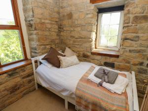 a bedroom with a bed in a stone wall at Pule Hill Farm in Huddersfield