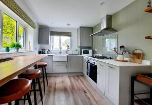 eine Küche mit weißen Schränken und einer Holzarbeitsplatte in der Unterkunft White Cottage Newport, Pembrokeshire in Newport