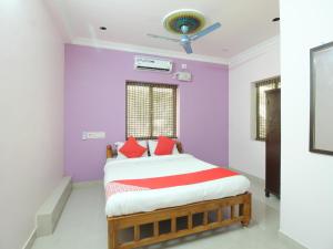 a bedroom with purple walls and a bed with red pillows at JMS Brahmin Guest House Thirunallar in Thirunallar