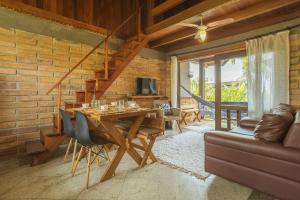 a living room with a wooden table and a couch at Villa Bali Casas pé na areia in Barra de Ibiraquera