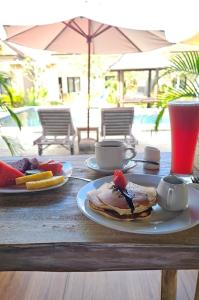 a wooden table with plates of pancakes and a drink at Uluwatu Jungle Villa in Uluwatu