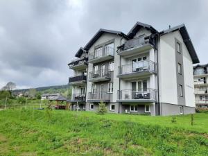 a large white building with balconies and a grass field at Apartamenty u Nataszy in Ustrzyki Dolne