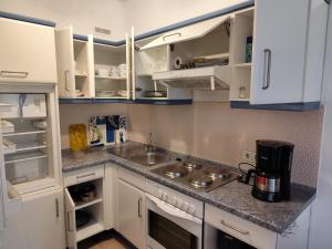 a kitchen with white cabinets and a sink at Lütte Hütte am Meer in Bad Zwischenahn