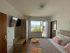 Schlafzimmer mit einem Bett, einem TV und einem Fenster in der Unterkunft Apartmani Braut in Kornić