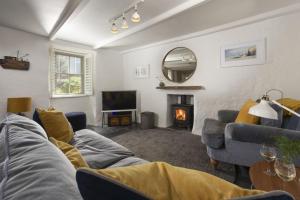 een woonkamer met een bank en een open haard bij Piskey Cottage, Mousehole - Close to Harbourside - Free WiFi - Free Parking in Mousehole