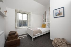 een witte slaapkamer met een bed en een raam bij Piskey Cottage, Mousehole - Close to Harbourside - Free WiFi - Free Parking in Mousehole