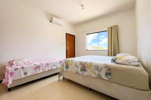 ein Schlafzimmer mit zwei Betten und einem Fenster in der Unterkunft Casa 5/4 Atalaia a 200m da Passarela do Caranguejo in Santa Maria